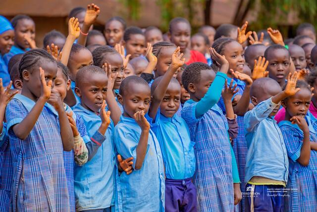 Schoolchildren with their hands raised at assembly during the tree planting