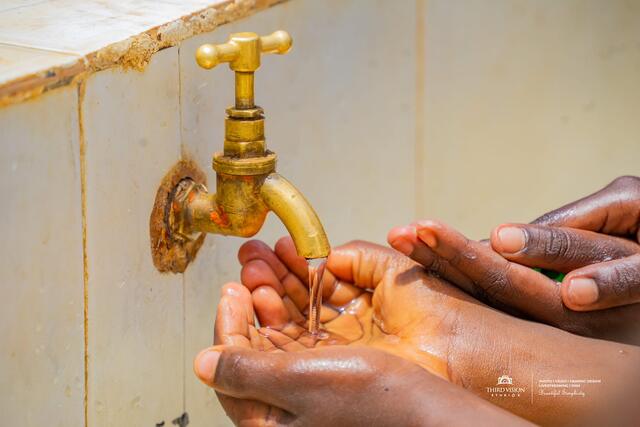 Water running from a tap over cupped hands at Kirigu Primary School