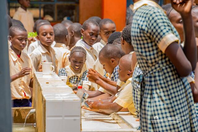 Pupils washing their hands at a row of basins on Global Handwashing Day