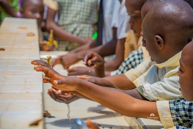 Pupils using the wooden handwashing station installed at the school